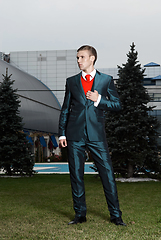 Image showing Portrait of an attractive young businessman in urban background wearing suit and necktie. Looking to the camera. Classic style.