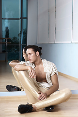 Image showing Man in elegant sport suit posing in fitness gym. Young man in gold sport leggings