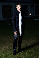 Image showing Male fashion, beauty concept. Portrait of young man with short wet hair wearing black suit, posing on street. Classic style.