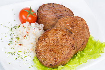 Image showing Three fried breaded cutlet with lettuce, tomatoes and rice on white background
