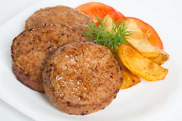 Image showing Three fried breaded cutlet with tomatoes and french fries on white background