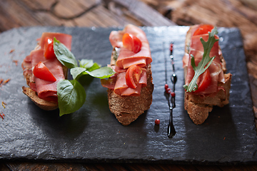 Image showing Bruschetta with hamon and sauce on black stone