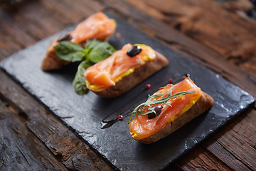 Image showing The tasty bruschetta with salmon on black stone