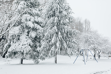 Image showing Child swing set dusted with snow in a snow covered parkland