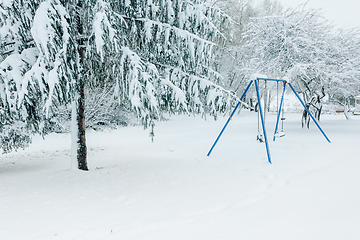 Image showing Swing set and trees in a park dusted and covered with fresh whit