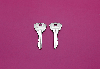 Image showing Two silver keys to english lock on bright crimson background