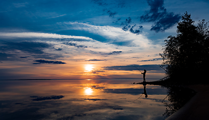 Image showing Woman fishing on Fishing rod spinning at sunset background.