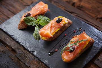 Image showing The tasty bruschetta with salmon on black stone