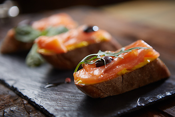 Image showing The tasty bruschetta with salmon on black stone