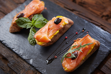 Image showing The tasty bruschetta with salmon on black stone