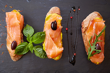 Image showing The tasty bruschetta with salmon on black stone