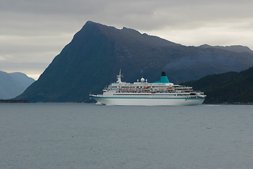 Image showing tourist ship sails into a fjord with mountains