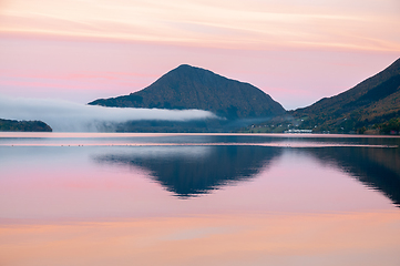 Image showing mountains reflected in the sea in pink light