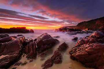 Image showing Vivid red sunrise over rocky beach coast