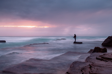 Image showing Stormy coast with a glimpse of sunrise through clouds