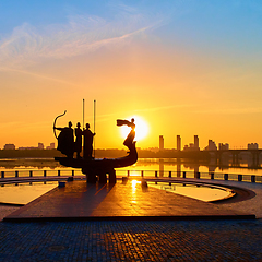 Image showing Monument to the founders of Kyiv at sunrise, wide-angle view with blue sky and yellow sun. Statue of Kyi, Shchek, Horyv and Lybid.