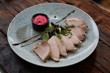 Image showing Sliced cold baked pork with herbs on blue plate