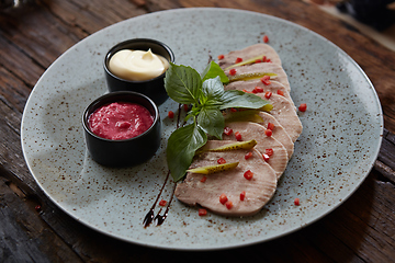 Image showing Sliced cold baked pork with herbs on blue plate