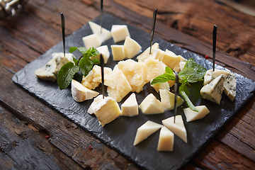 Image showing Cheeseboard Top View on Black Stone Plate Background