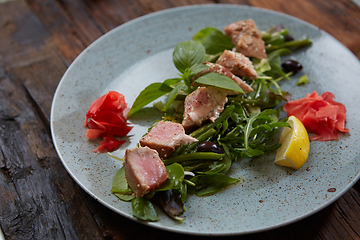 Image showing beautiful food: steak tuna in sesame, lime and fresh salad close-up on a plate on the table.