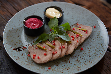 Image showing Sliced cold baked pork with herbs on blue plate