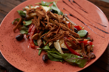 Image showing Salad baked eggplant with green onions, croutons and tomatoes on wooden background.