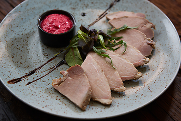 Image showing Sliced cold baked pork with herbs on blue plate