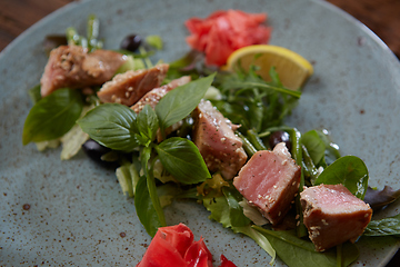Image showing beautiful food: steak tuna in sesame, lime and fresh salad close-up on a plate on the table.