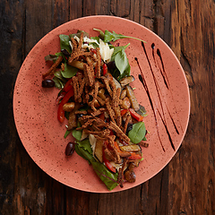 Image showing Salad baked eggplant with green onions, croutons and tomatoes on wooden background.