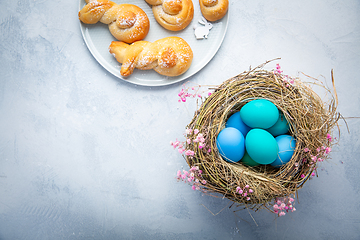 Image showing Easter eggs in nest with sweet buns made from yeast dough in a s