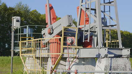 Image showing Operating oil and gas well in oil field, profiled against the blue sky