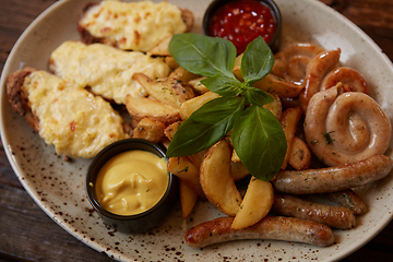 Image showing Grilled assorted sausages with French fries, bruschettes with cheese and sauces.