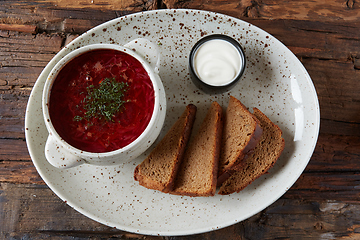 Image showing Traditional Ukrainian Russian borscht with white beans on the bowl. Plate of red beet root soup borsch on black rustick table. Beetroot soup Top view. Traditional Ukraine food cuisine