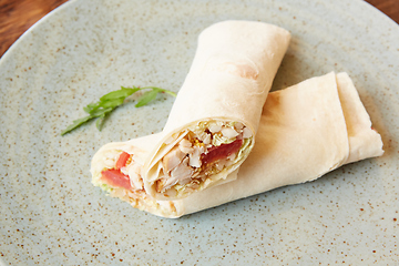 Image showing Lavash roll with chicken and vegetables close up on a plate. horizontal