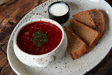 Image showing Traditional Ukrainian Russian borscht with white beans on the bowl. Plate of red beet root soup borsch on black rustick table. Beetroot soup Top view. Traditional Ukraine food cuisine