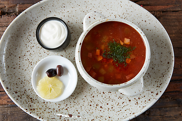 Image showing Soup saltwort with lemon, meat, pickles, tomato sauce olives in a bowl on a sacking.