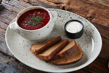 Image showing Traditional Ukrainian Russian borscht with white beans on the bowl. Plate of red beet root soup borsch on black rustick table. Beetroot soup Top view. Traditional Ukraine food cuisine