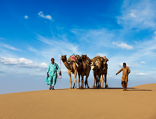 Image showing Two cameleers (camel drivers) with camels in dunes of Thar deser