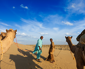 Image showing Two cameleers (camel drivers) with camels in dunes of Thar deser