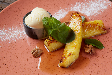 Image showing Grilled pineapple with scoops of vanilla ice cream.
