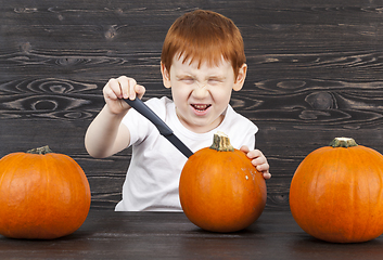 Image showing redhead boy with red pumpkins