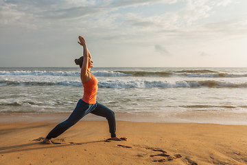 Image showing Woman doing yoga asana Virabhadrasana 1 Warrior Pose on beach on