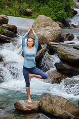 Image showing Woman in yoga asana Vrikshasana tree pose at waterfall outdoors