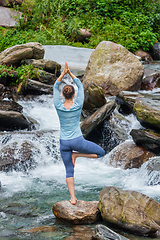 Image showing Woman in yoga asana Vrikshasana tree pose at waterfall outdoors