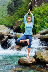 Image showing Woman in yoga asana Vrikshasana tree pose at waterfall outdoors