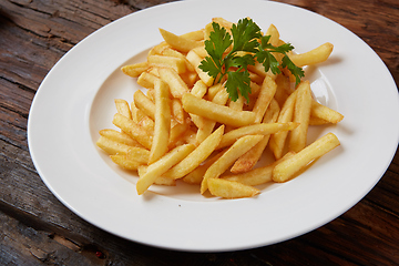 Image showing French fries in a bowl on a wooden background.