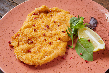 Image showing Chicken schnitzel on plate over wooden background, Top view