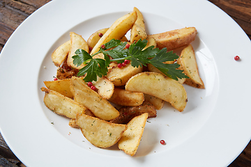 Image showing Homemade roasted potato with parsley on rustic background.