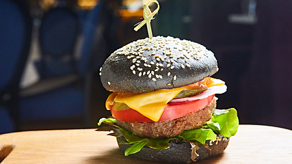 Image showing Japanese Black Burger with Cheese. Cheeseburger from Japan with black bun on dark background.
