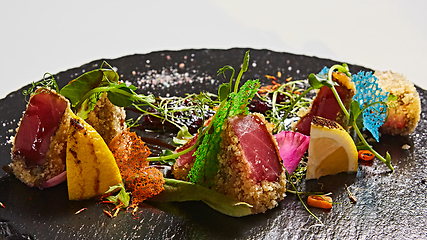 Image showing Close up of rare seared Ahi tuna slices with fresh vegetable salad on a plate.